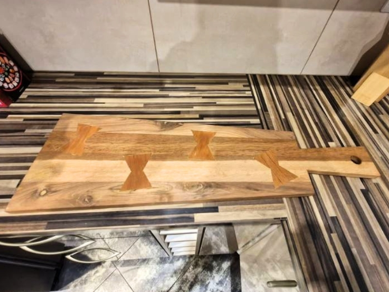 Planche à découper artisanale associant orme et chêne bicolore, décorée d'incrustations papillons en bois exotique.