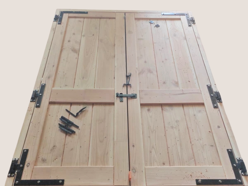 Porte double artisanale en bois de Douglas avec quincaillerie noire, fabriquée sur mesure pour un abri de jardin.
