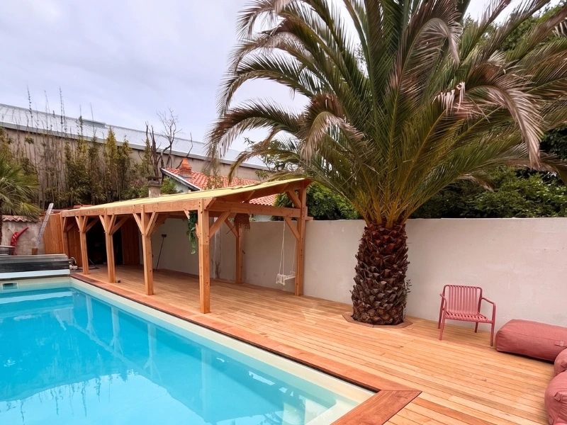 Aménagement extérieur sur mesure avec une terrasse en bois exotique autour d'une piscine, surplombée d'une grande pergola en Douglas.